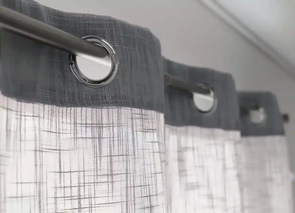 Rows of freshly cleaned white linens stacked on metal racks in a spacious industrial laundry facility with large windows.