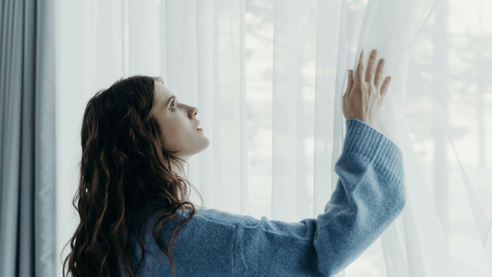 Curtain cleaning cost Auckland: A woman checking if her curtains need cleaning