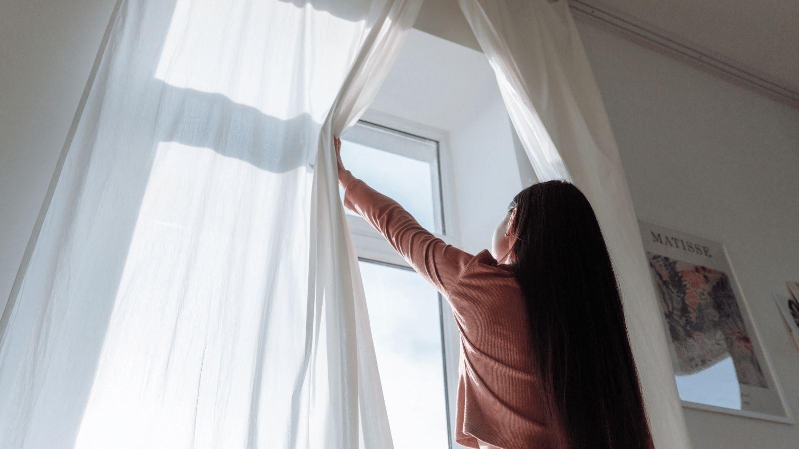 How often should you clean curtains: Picture of a girl opening curtains